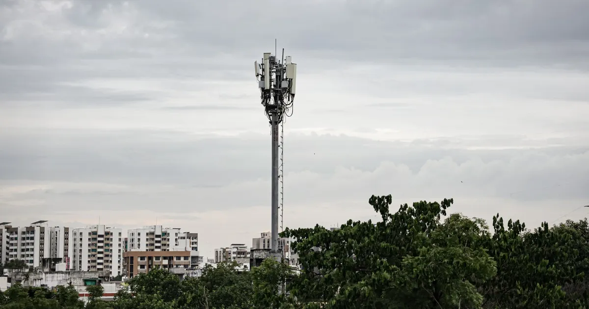 Torre de telefonia em meio a prédios urbanos reflete pressão no varejo e resiliência da TIM e Vivo.