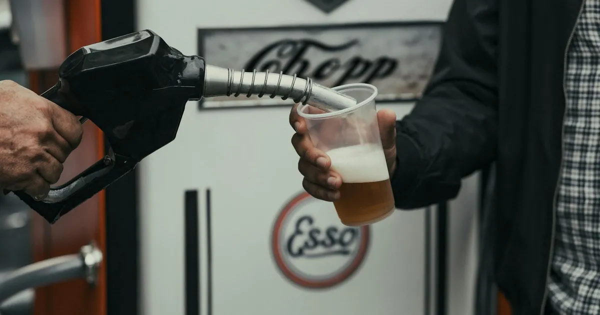 Bico de bomba vintage abastecendo copo, simbolizando biocombustíveis, etanol e impacto nos preços dos combustíveis no posto.