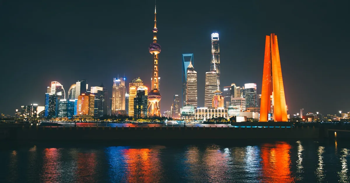 Skyline de Xangai iluminado, símbolo do PIB da China em desaceleração e alerta à economia global.