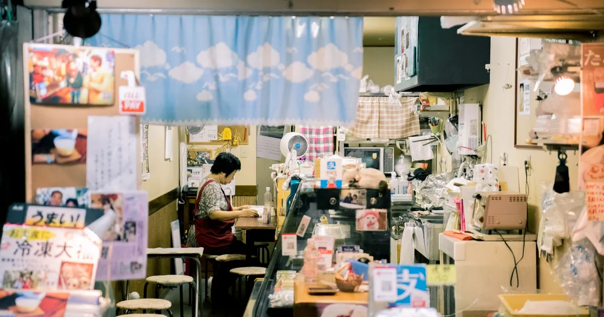 Mulher asiática trabalhando em loja de comércio em Osaka, refletindo novas regras de trabalho em feriados.