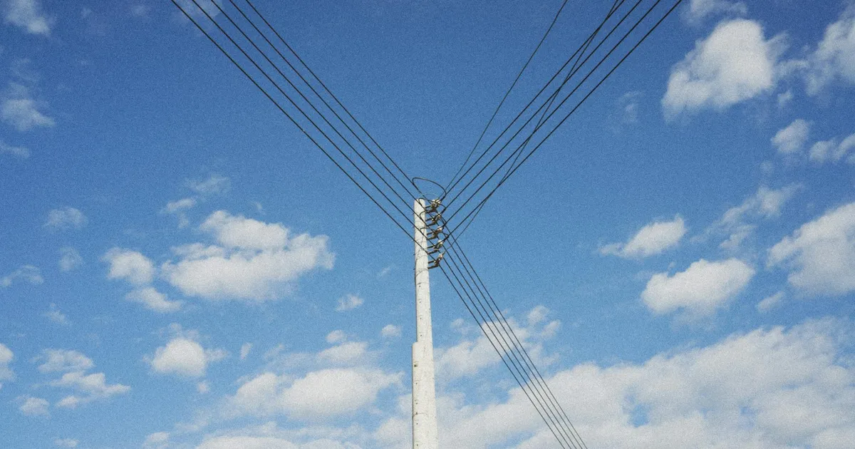 Tarifas de energia mais baratas: céu azul sobre linhas de transmissão simboliza a bandeira verde da Aneel aliviando contas.