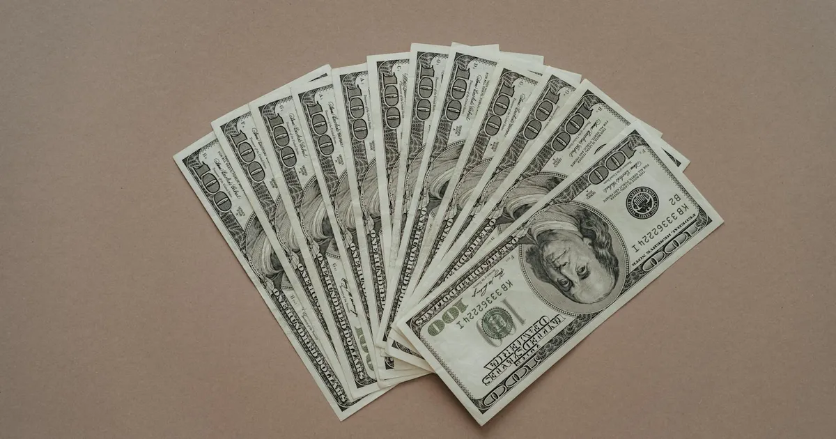 Cédulas de dólar em leque, destacando o fluxo cambial, o déficit na conta corrente e as contas externas do Brasil.