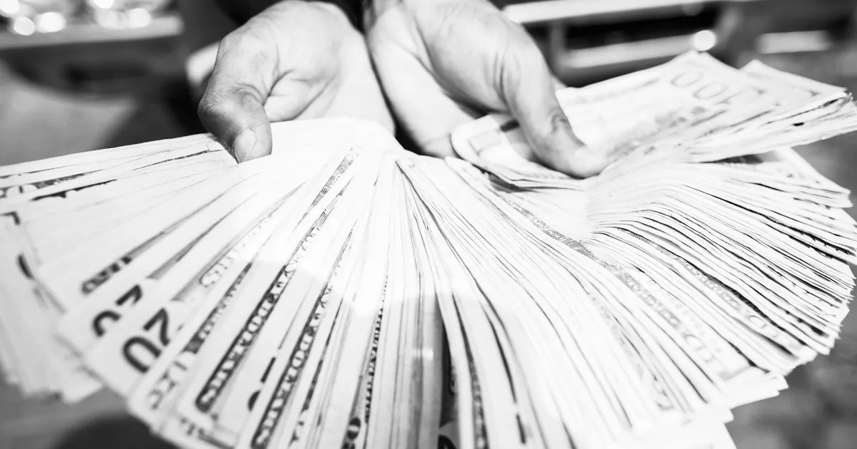 Mãos segurando dinheiro, os R$ 730 mi em dinheiro público congelados pela justiça no RJ.