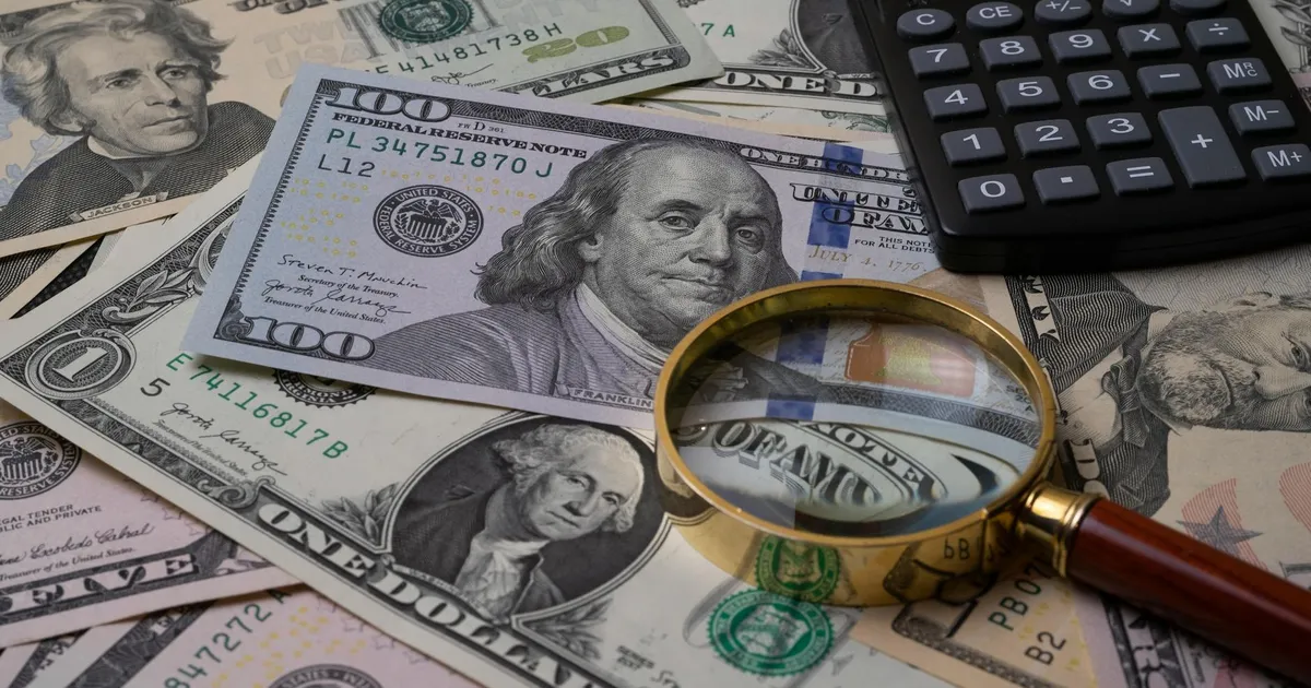 Análise financeira de dividendos: lupa e calculadora sobre notas de dólar. Petrobras, CSN Mineração, TIM e proventos.