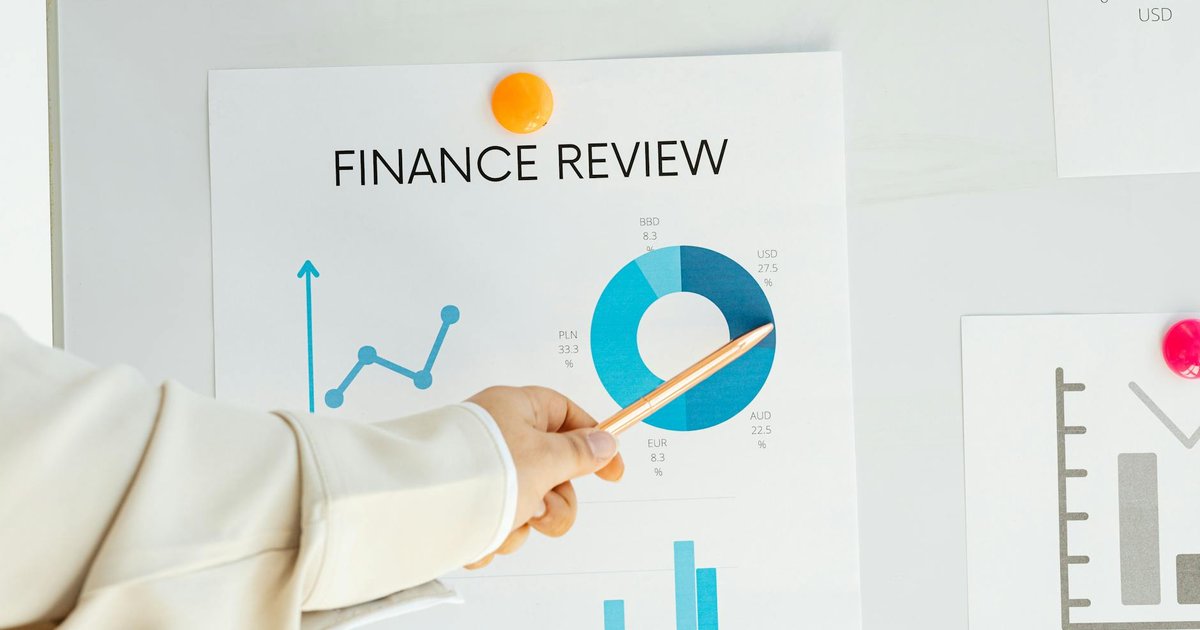 Mão apontando relatório financeiro com gráficos. Guia sobre o que é e como calcular Ebitda.