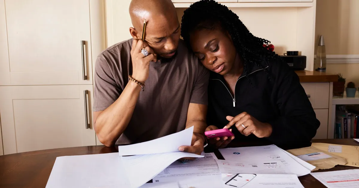 Casal planeja finanças domésticas, férias e crédito, usando smartphone para gerenciar grana do dia a dia.