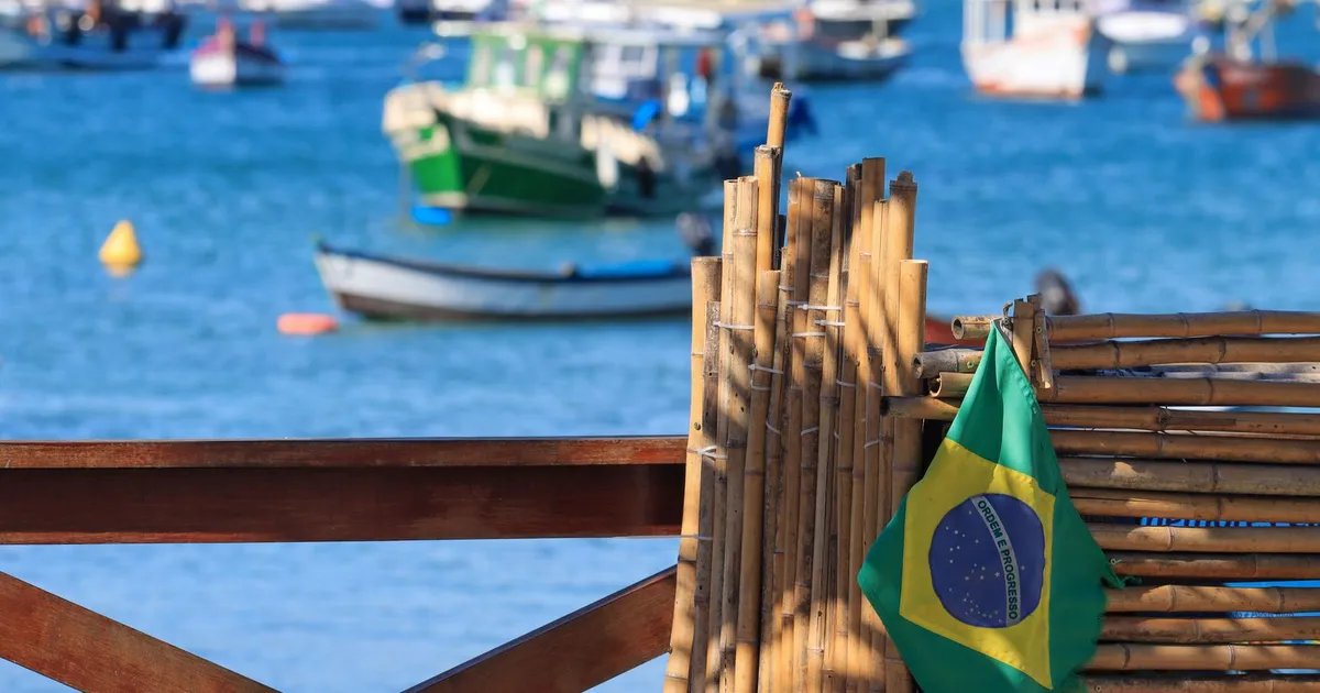 Bandeira do Brasil em porto, representando comércio exterior e tarifas sobre etanol e açúcar.