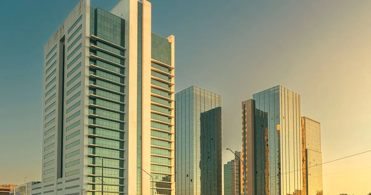 Febraban apoia Banco Central; prédios modernos no pôr do sol em Porto Alegre.