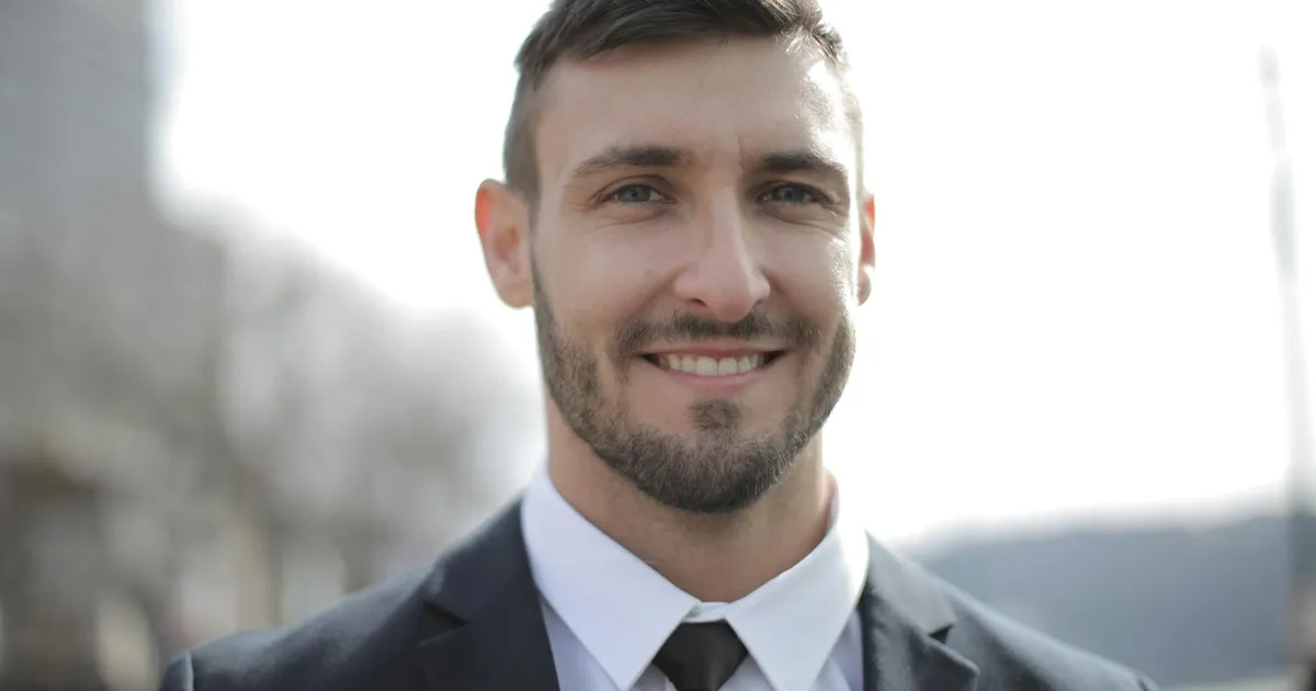 Fundador do Nubank reconhecido pela Forbes, sorrindo em traje social.