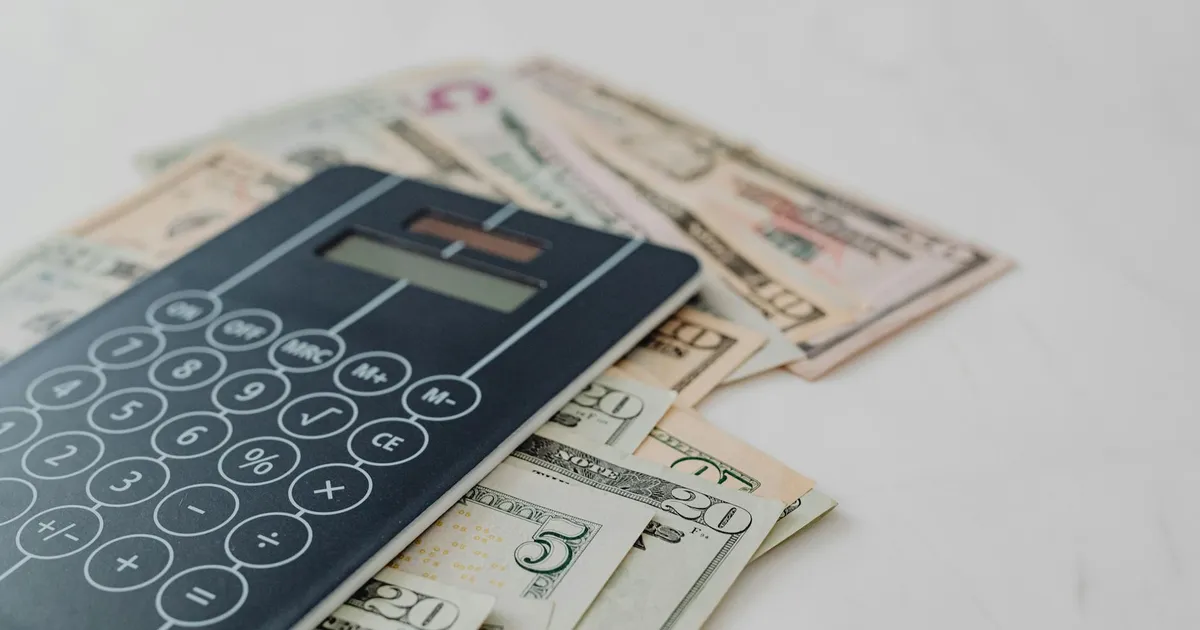 Gastos públicos: calculadora e notas de dólar ilustram impacto de R$215 bi no orçamento e custo de vida.