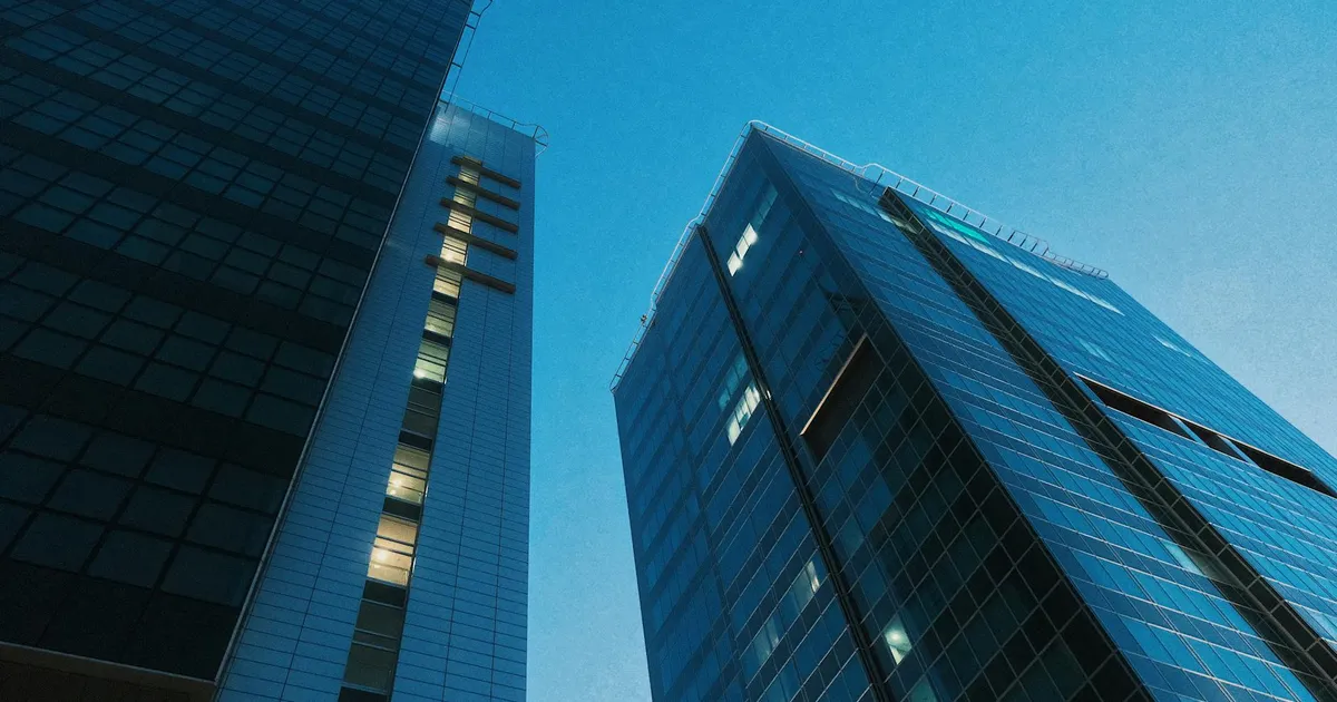 Arranha-céus modernos de vidro simbolizam os gigantes do mercado tech no pós-mercado, com resultados trimestrais.