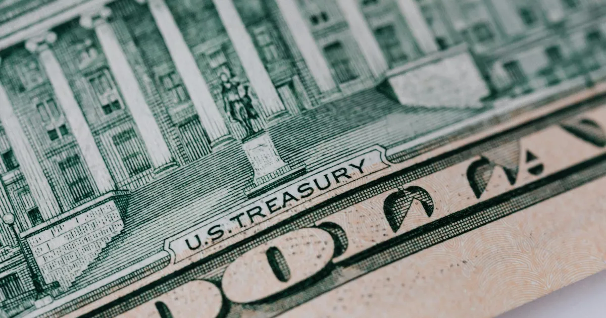 Dólar americano em close, simbolizando o impacto da guerra no Irã na economia brasileira: petróleo, inflação e PIX.