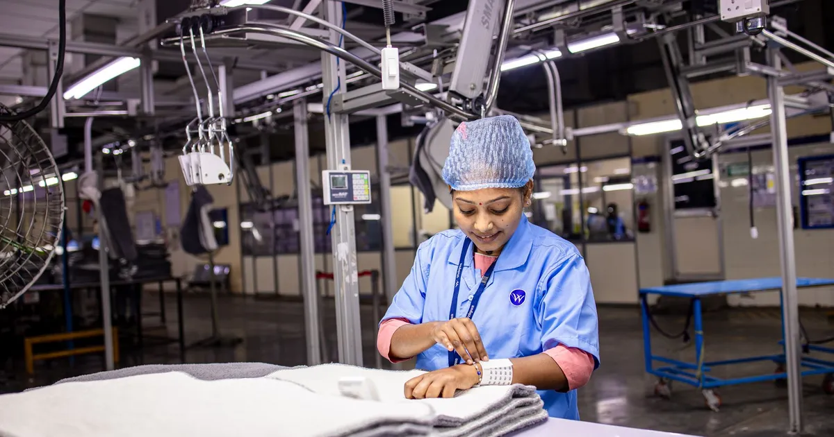 Mulher em fábrica têxtil moderna, focando em trabalho, em meio a demissões e dilemas da IA no setor.