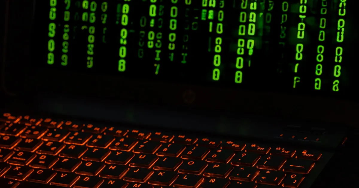 Teclado de laptop com código digital verde: IA, dinheiro e segurança cibernética no mercado financeiro.