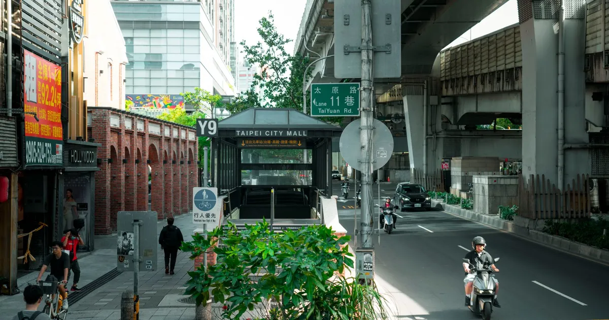 IA em Taiwan: Rua vibrante de Taipei com centro comercial e motos, ecoando revolução tecnológica e em investimentos.