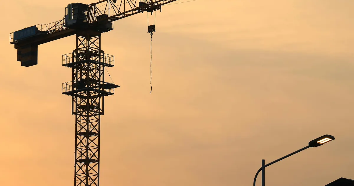 Guindaste em construção ao pôr do sol. Desempenho do Ibovespa e desafios do setor da construção civil (Cyrela, Gerdau).
