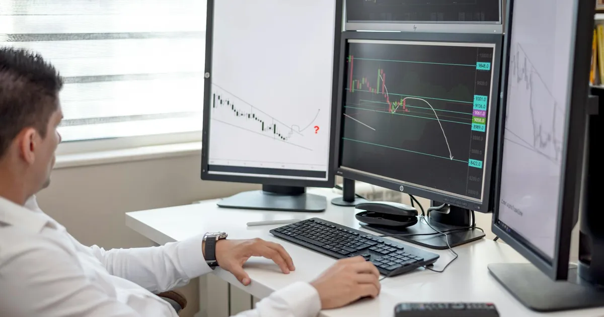 Homem analisa gráficos financeiros no escritório: Ibovespa, Payroll EUA e IA impactam o mercado.