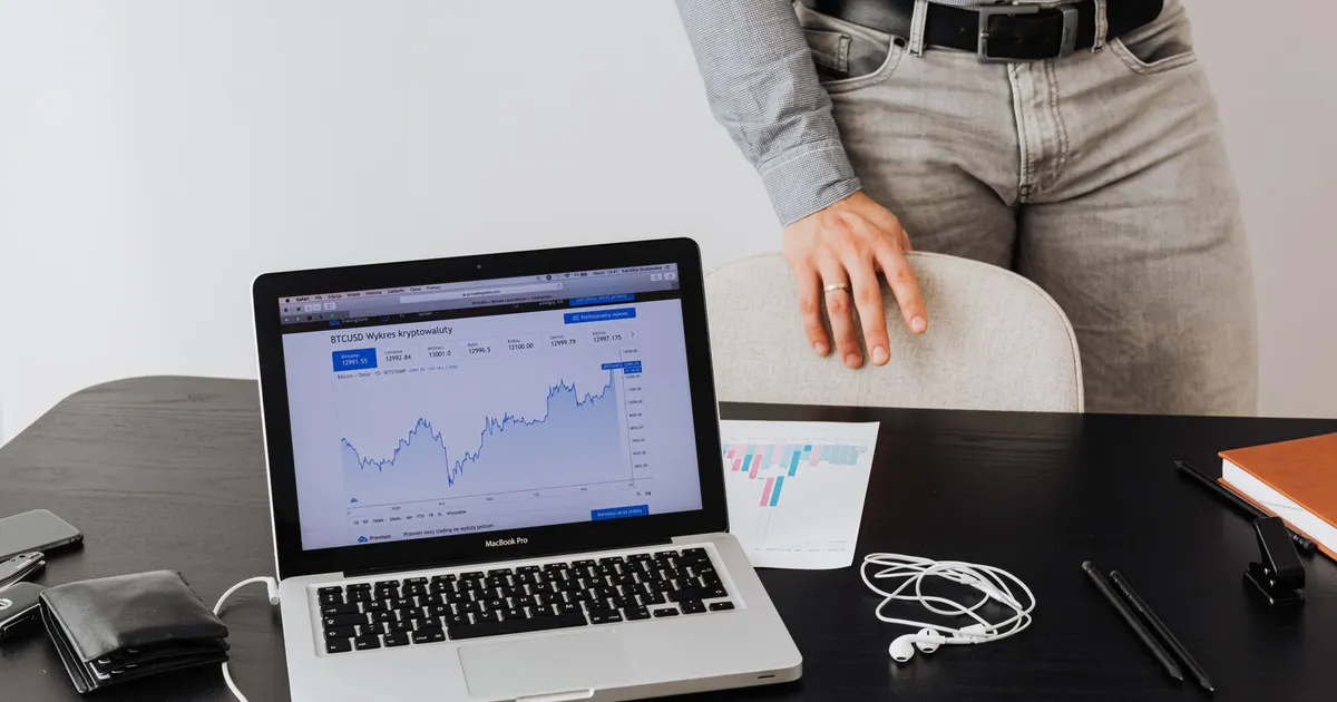 Homem de terno analisa dados de criptomoedas em laptop, cenário para recuo da Bolsa brasileira e alta do dólar.