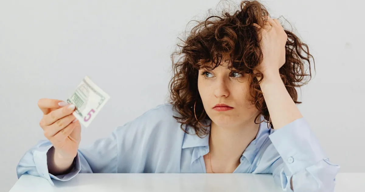 Preocupação com dívidas: mulher analisa nota de dólar. Inadimplência alta no Brasil impacta finanças.