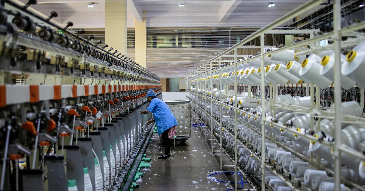 Trabalhadora têxtil em fábrica moderna, representando aperto na indústria brasileira de elétricos.
