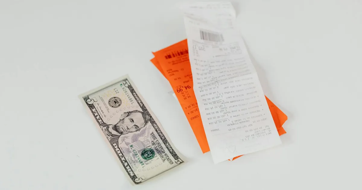 Inflação no Brasil: Nota de 5 dólares e recibos simbolizam impacto no bolso. Selic e renda fixa em foco.