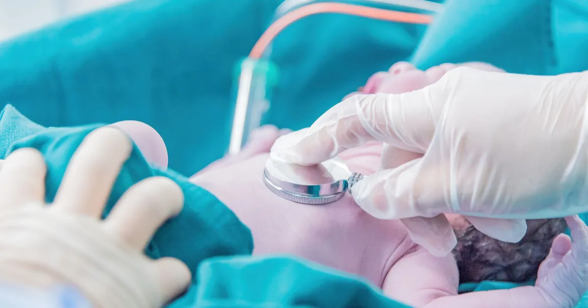 Médico examina recém-nascido, alertando para internações de bebês com doenças respiratórias no inverno.