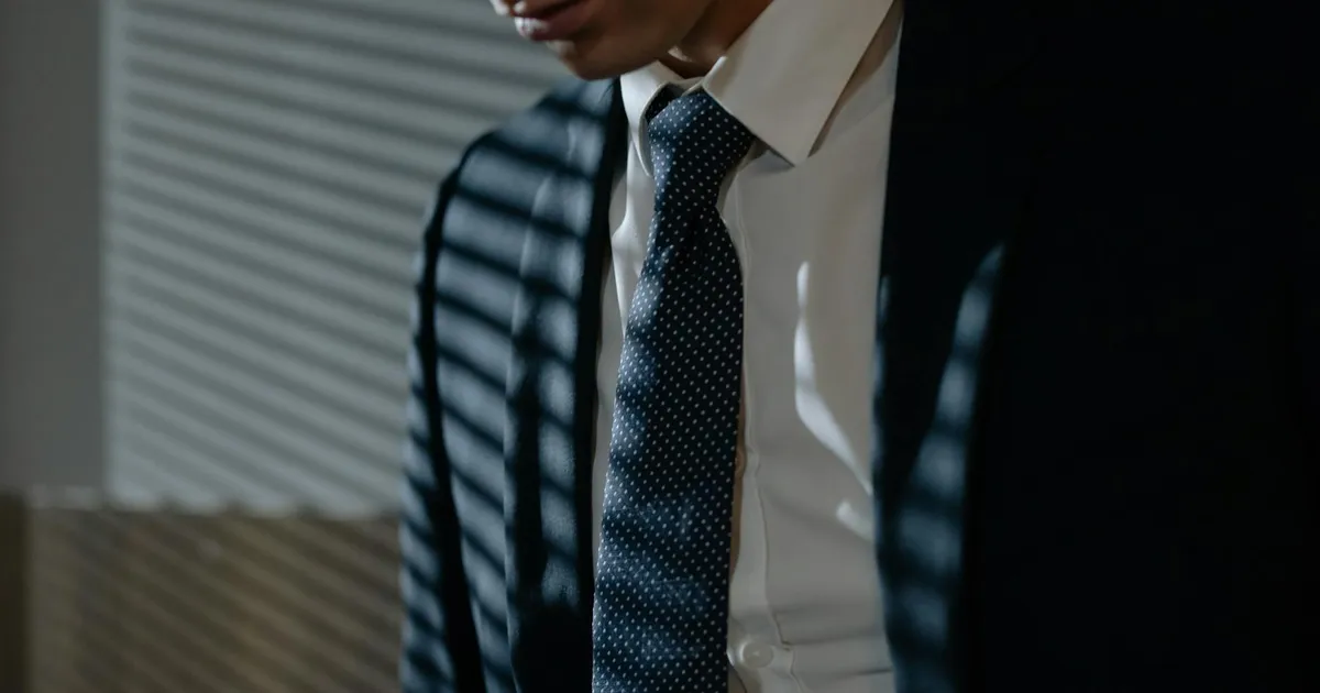 Novo chefe do Federal Reserve em terno sob sombras listradas, ilustrando a complexidade da política monetária e juros EUA.