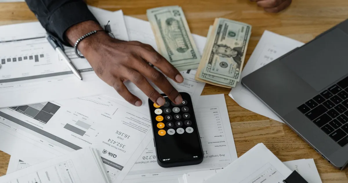 Documentos financeiros com calculadora, dinheiro e laptop refletem o impacto da Selic e juros no Brasil.
