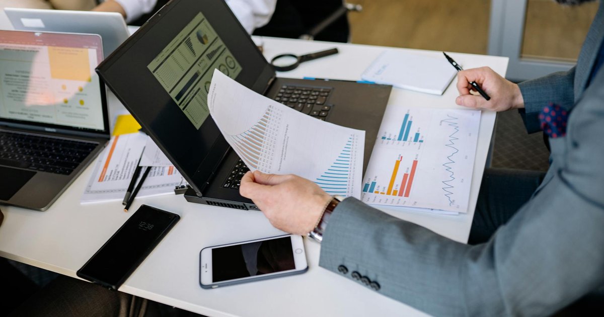 Profissionais em reunião, analisando gráficos em notebooks para conformidade LGPD 2026.