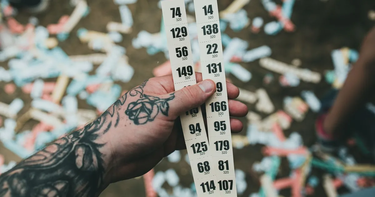 Mãos tatuadas com bilhetes de lotofácil, simbolizando a busca por um milagre financeiro na economia.
