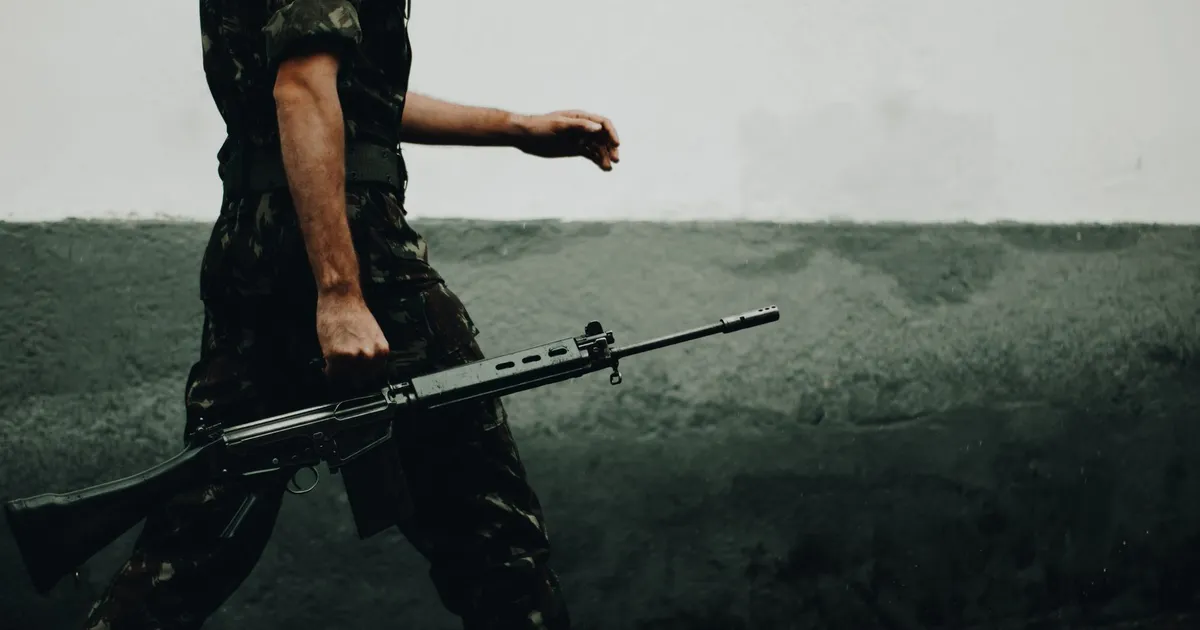 Soldado em camuflagem com fuzil reforça defesa nacional e soberania defendidas por Lula.