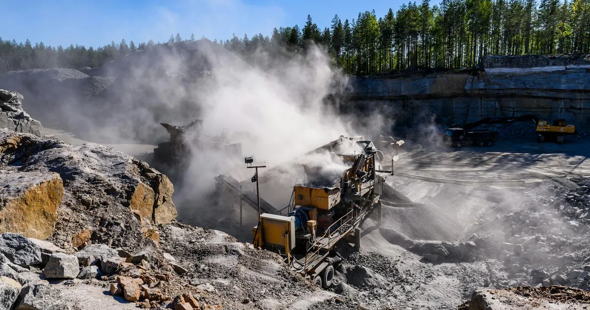 Maquinário de escavação em pedreira poeirenta. Ilustra mineração de minerais críticos e debate sobre política ambiental.