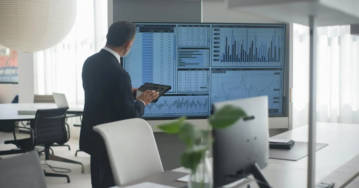 Profissional foca em dados financeiros e PMIs na tela, interpretando o mercado de trabalho e a economia global.