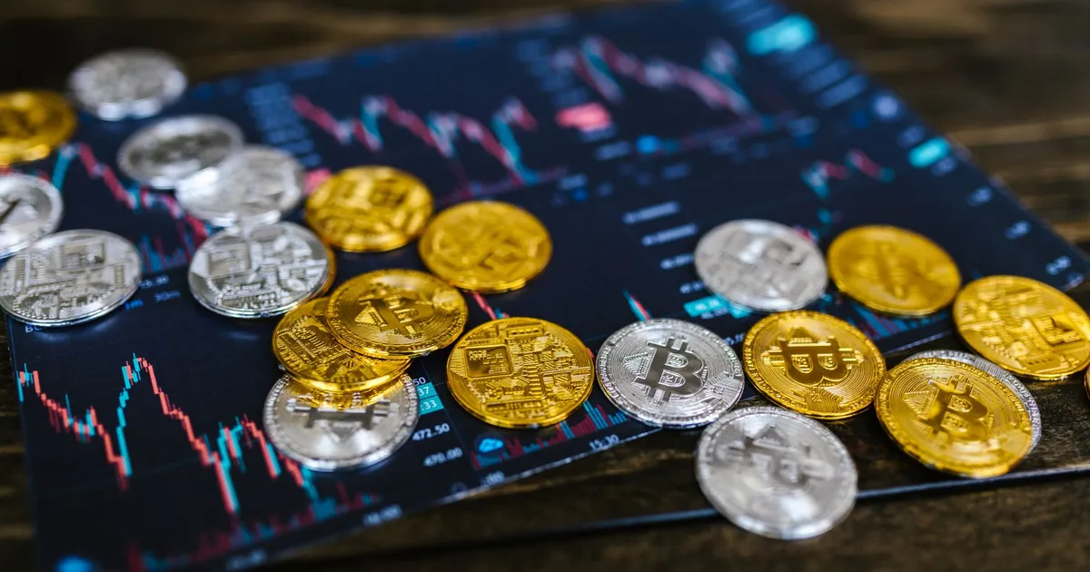 Ouro e Bitcoin caem em gráfico financeiro. Metais e criptomoedas em baixa.