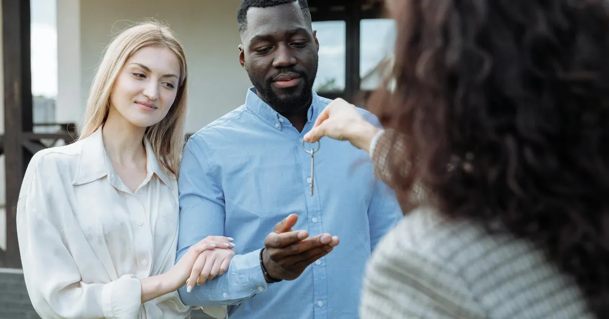 Casal feliz recebe chaves de sua casa nova, resultado do Minha Casa Minha Vida para famílias.