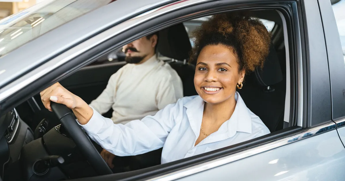 Mulher testa carro em concessionária, refletindo mudanças para montadoras e locadoras no Move Brasil.