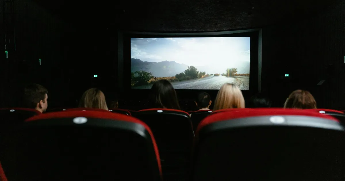 Pessoas assistem filme no cinema: Netflix e resultados trimestrais em foco após balanço.