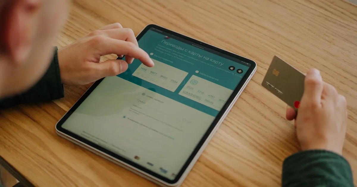 PicPay e BRB investigados por fraude na folha de pagamento, homem usa tablet e cartão para pagamento online.