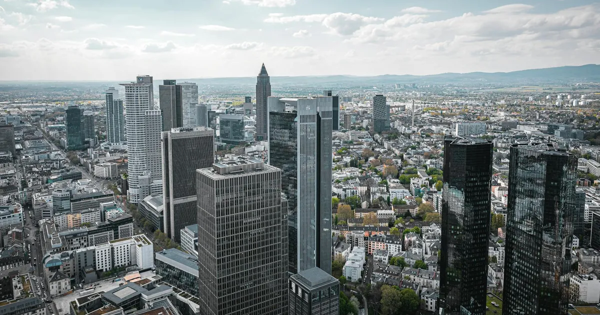 Cenário financeiro global: Frankfurt ao fundo, com foco nas decisões do Payroll EUA e impacto na Selic e dólar.