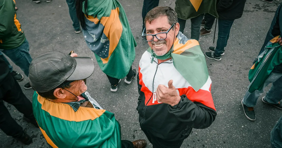 Eleições 2026: apoiadores com bandeiras do Brasil. Debate Lula x Bolsonaro, STF e cotas raciais.