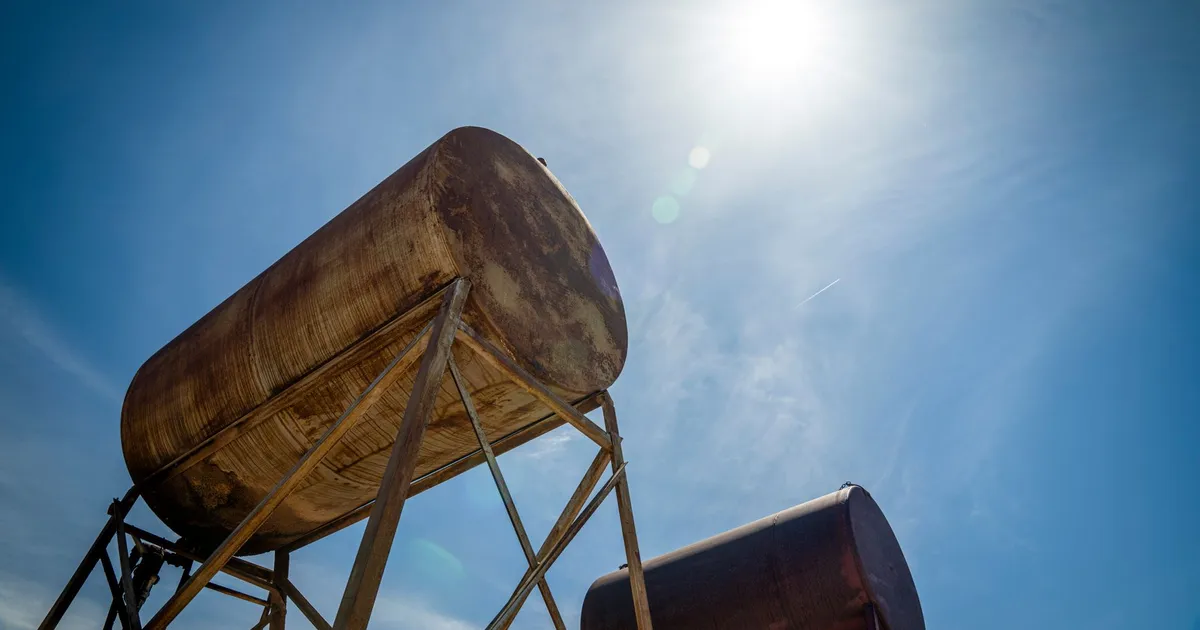 Tanques de petróleo EUA-Irã sob céu azul, com queda do preço do petróleo após acordo geopolítico.