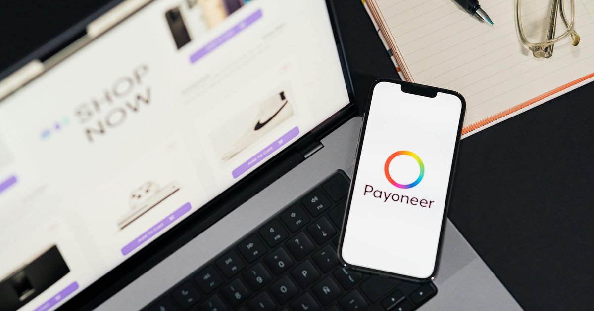 Celular com app Payoneer e laptop em site de compras, relacionado a cancelamento de Pix em 2026.