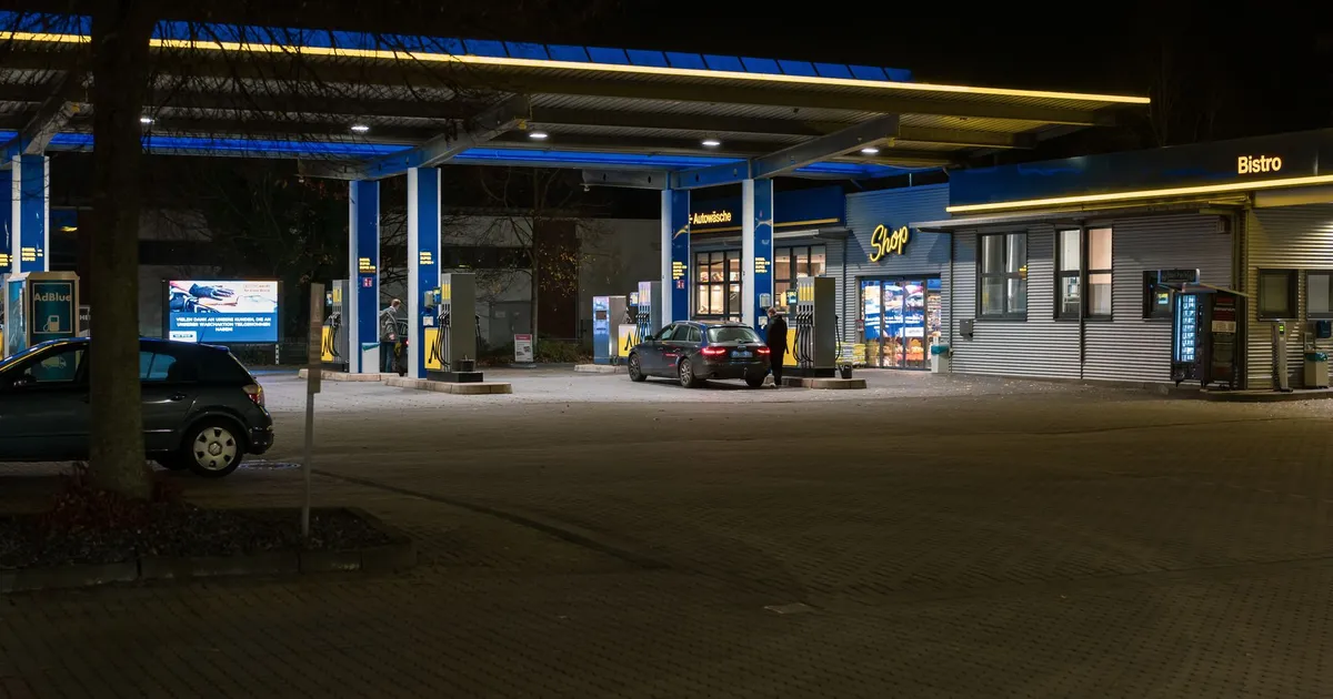 Posto de gasolina com carros e bistrô à noite, cenário urbano vibrante para discussão sobre Pix e preços em postos.