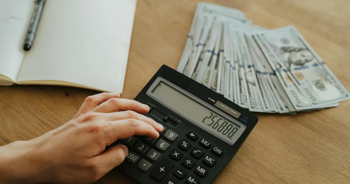 Cálculo da restituição do Imposto de Renda 2026: mão com calculadora e dinheiro. Receita Federal turbina IRPF.