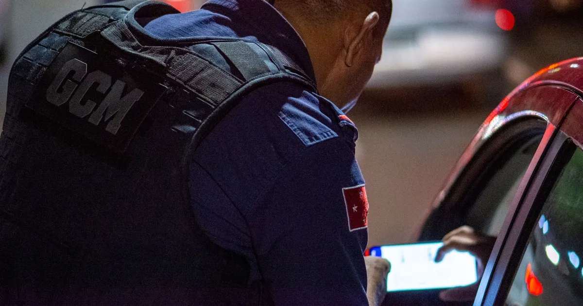 GCM verifica documentos em controle noturno em Londrina, Brasil, cenário de insegurança.