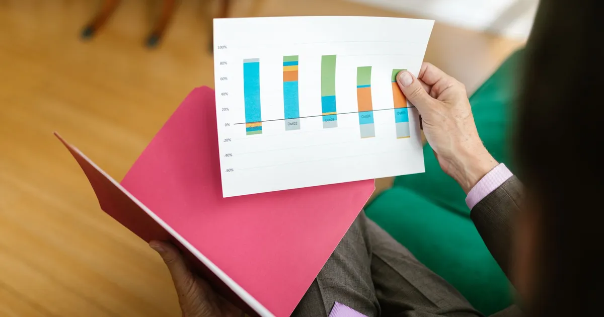 Pessoa analisa gráfico de relatório de negócios sobre impacto do corte da Taxa Selic no setor produtivo brasileiro.