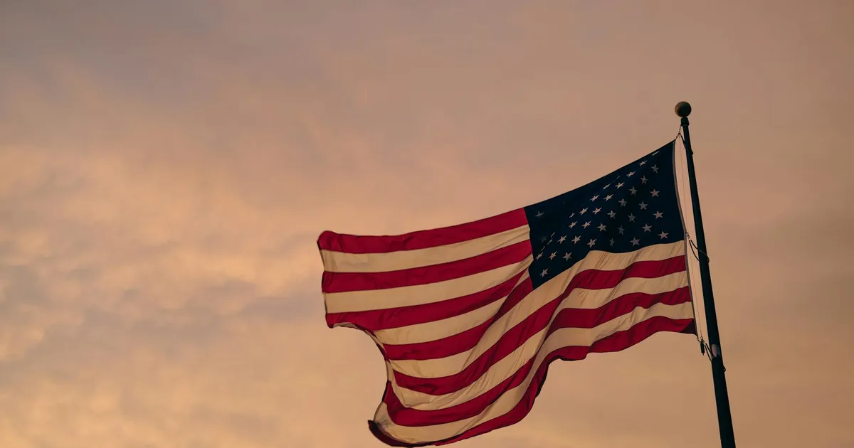 Bandeira dos EUA ao pôr do sol. Impacto da tensão EUA-Irã no Brasil: Lula, Petrobras e economia.