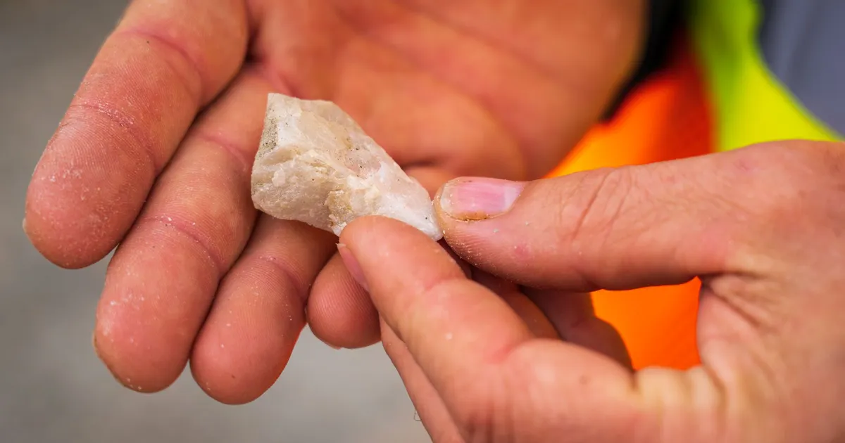 Mãos exploram rocha de terras raras no Brasil, indicando pesquisa mineral estratégica e industrialização.
