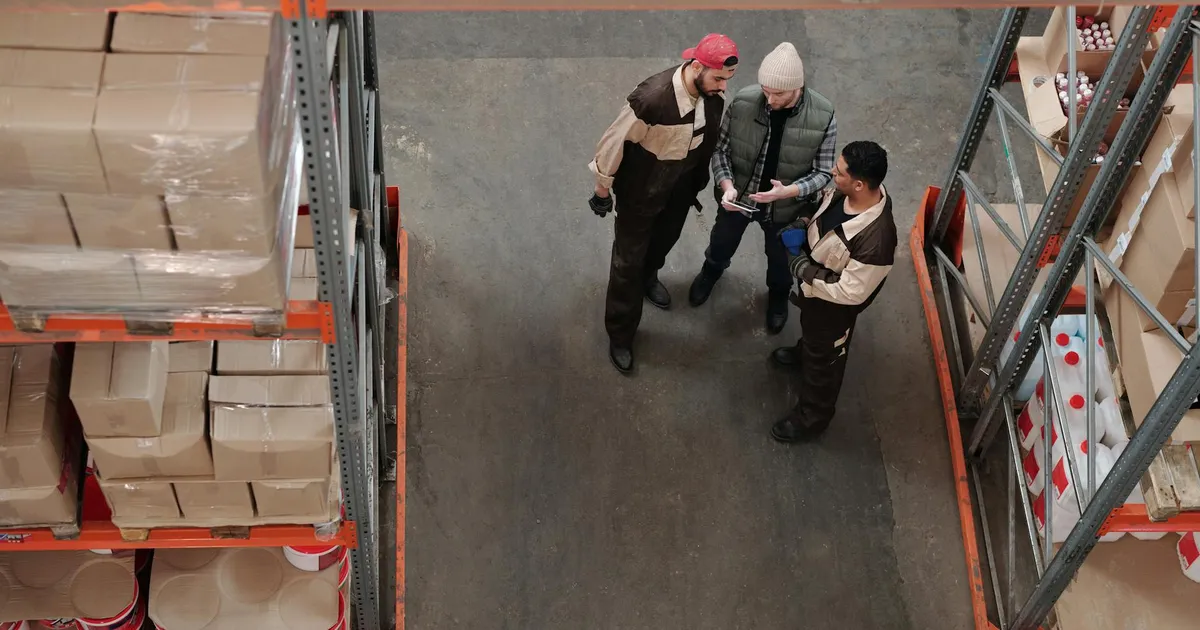 Trabalhadores discutem logística em armazém, como em Klabin e Vale, no setor industrial.