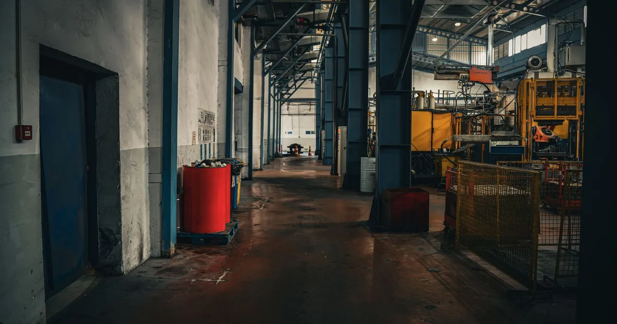 Fábrica da Volkswagen na Europa com maquinário, contexto de corte de 100 mil empregos e demissões.